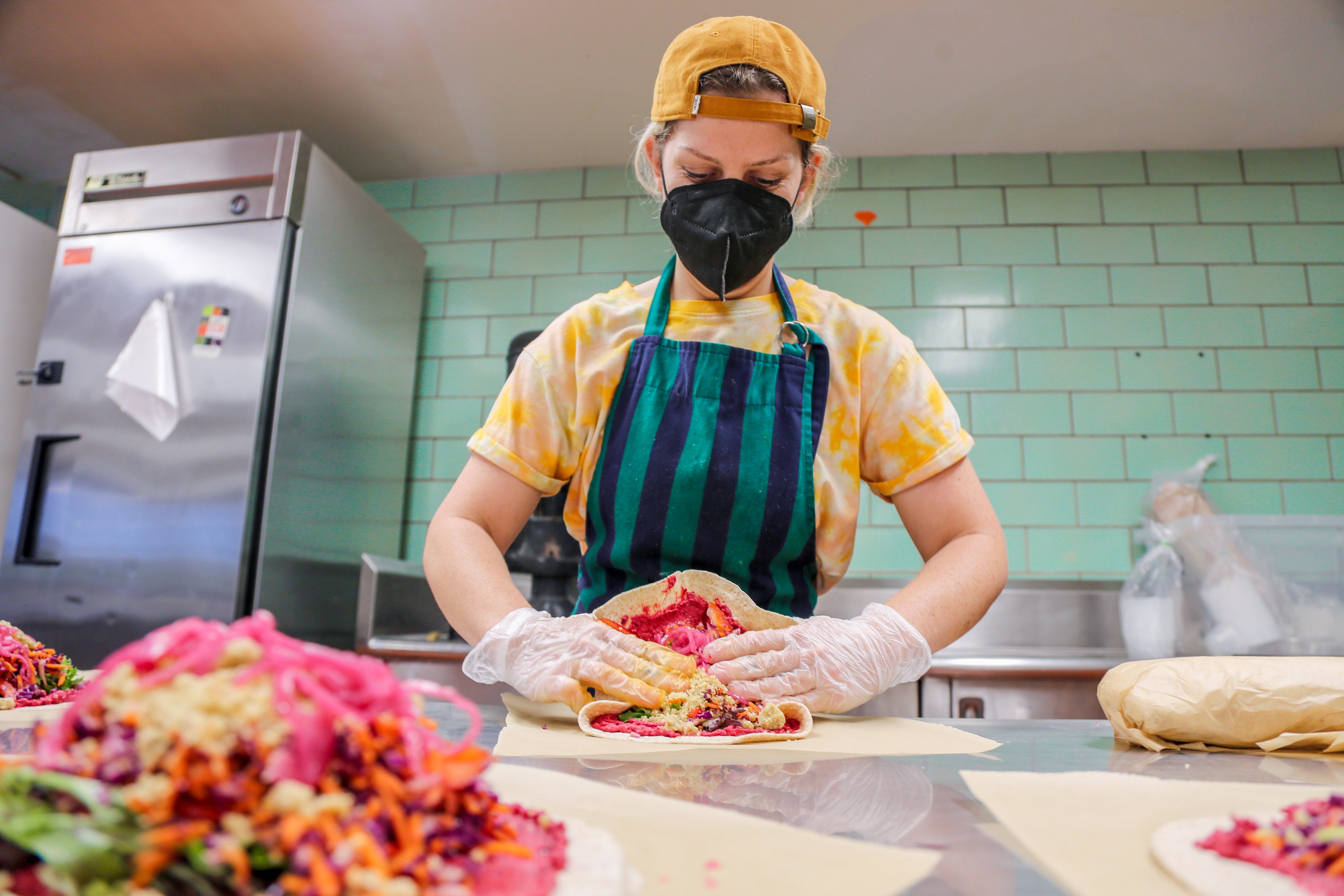 An employee makes beet hummus wraps at New World Kitchen in Des Moines, Iowa