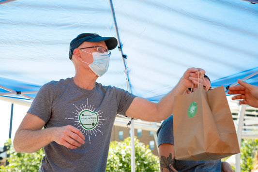Chef Steve Bryce handing a customer an order at the VegLife Vegan Market in Des Moines, Iowa